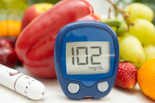 hand holding digital glucose monitor measure with vegetable and fruit healthy food. photo