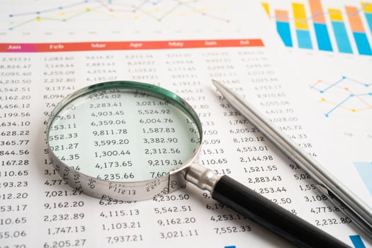 Magnifying glass on spreadsheet and graph paper. Financial data economy photo
