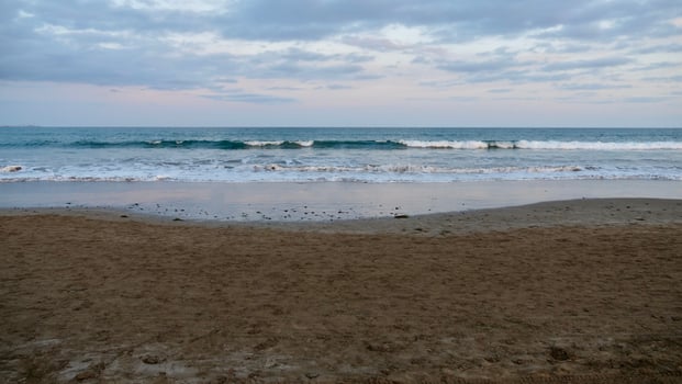 A person is standing on the beach with a surfboard photo