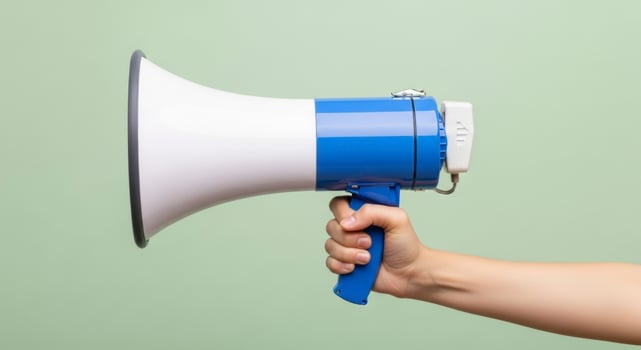 Human hand holding a blue and white megaphone for communication and public announcement photo
