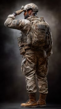 Soldier in military uniform saluting with a tactical backpack in a studio setting during a dramatic lighting session photo