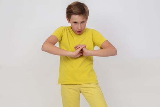 A young guy in a yellow shirt stands with his arms crossed and looks at the camera. photo