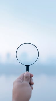 Hand holding a magnifying glass against a blurred background, emphasizing clarity and focus, symbolizing exploration and discovery in a serene environment photo