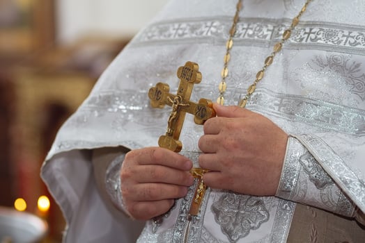 An Orthodox priest in clothes with a golden cross in his hands in the church. Orthodox tradition and faith. Equipment for prayer photo