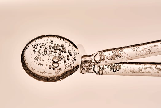 A serum pipette with bubbles on a beige background. photo