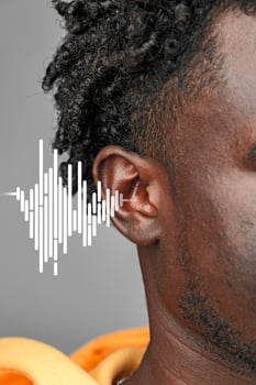 Sound waves visually represented near ear of a man wearing an orange hoodie in an urban style shoot photo