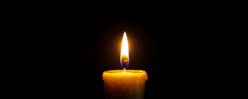 Warm glow of a candle flame in darkness. A single candle illuminated in a dim environment, with a vibrant flame flickering gently as droplets adorn its surface. photo