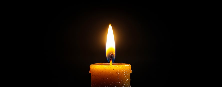 Candle flame glowing in dark environment. A single candle burns brightly in a dark space, casting warm light and creating a tranquil atmosphere. photo