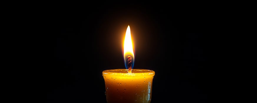 Candle flickering in dark background. A single candle burns brightly in a dark setting, creating a warm and serene atmosphere with its gentle glow. photo