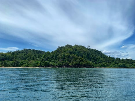 a small island in the middle of the ocean with blue sky and white clouds photo