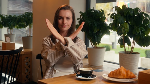 Portrait negative Caucasian woman crossed hands no not stop reject gesture sitting in cafe businesswoman female business girl looking at camera answer disagree deny keep distance protect crossing arms photo