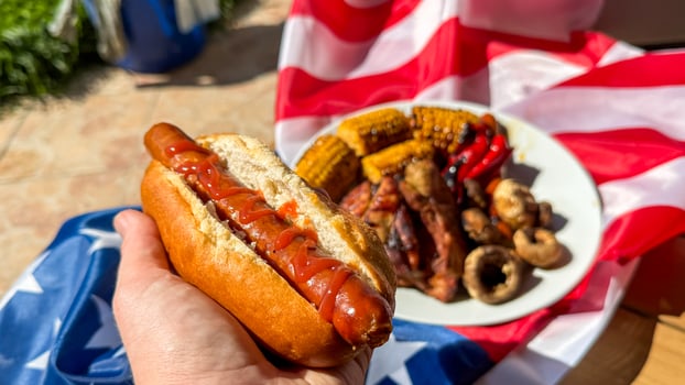 Barbecue symphony of sizzling hot dogs and corn on patriotic fabric evokes Fourth of July merriment, culinary celebration photo