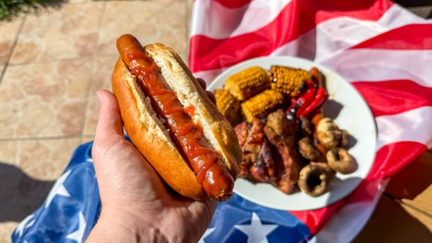 Hand grasps sauce drizzled hotdog, evoking Fourth of July exuberance and backyard grilling, multicultural celebration, gastronomic freedom festivity photo