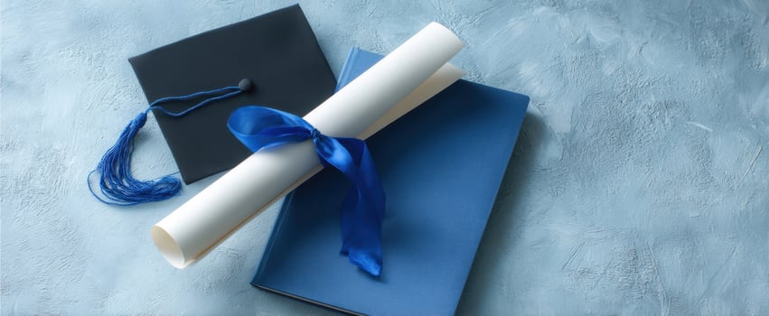 The graduation cap and diploma with books on a textured blue background. photo