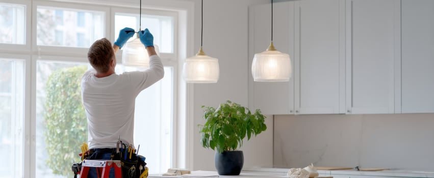 The handyman installing modern pendant lights in a beautifully renovated kitchen. photo