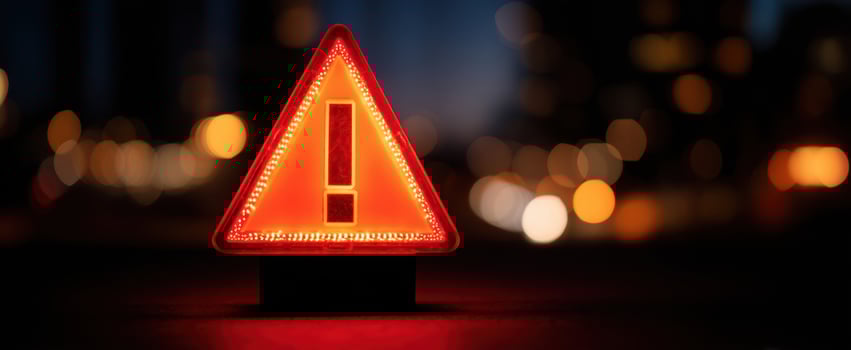 The illuminated warning sign stands out against the night backdrop of the city. photo