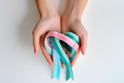 Lightskinned hands carefully hold a pastel pink and teal striped ribbon on white photo