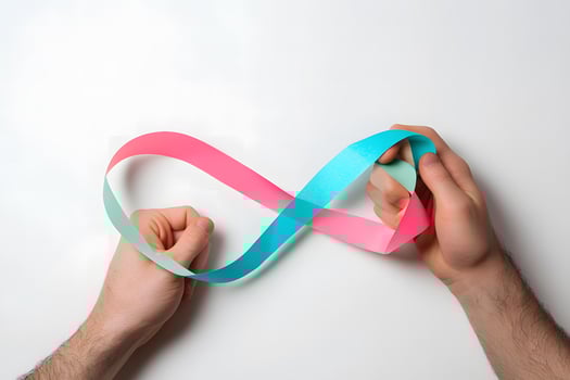 Caucasian hands manipulate a pink and blue paper strip into an infinity symbol shape photo