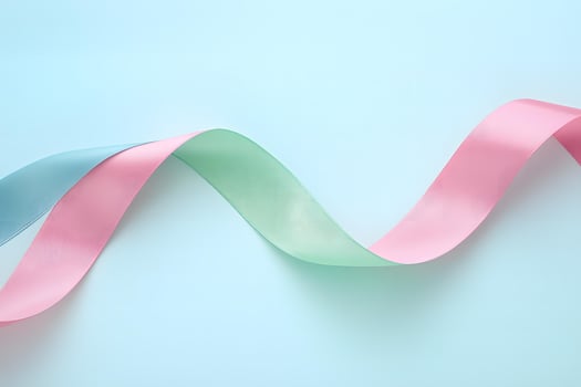 Wavy pink and teal ribbons intertwine elegantly against a soft light blue backdrop, creating harmony photo