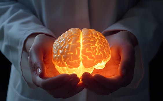 Human hands tenderly hold an illuminating, glowing human brain, indicating care and understanding photo