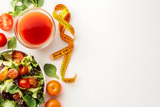 A colorful tomato salad, juice, and a tape measure showcase health and diet photo