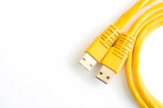 Two bright yellow USB cables are seen looped against a clean white background photo