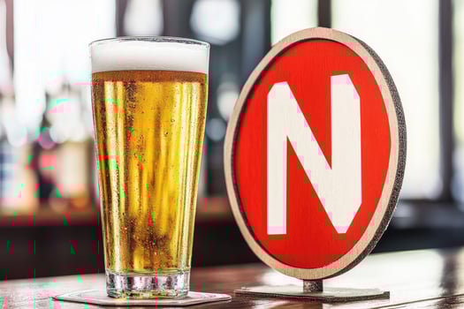 A refreshing light beer in a tall glass, on a bar top, next to a red sign photo