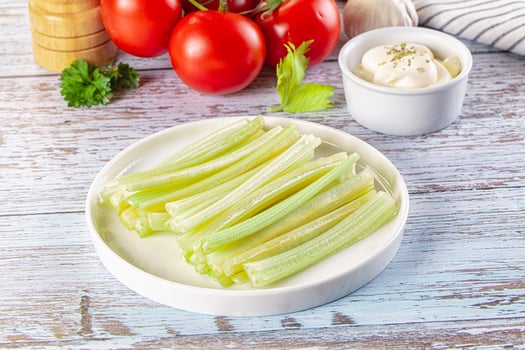 A plate of celery with a bowl of sour cream photo