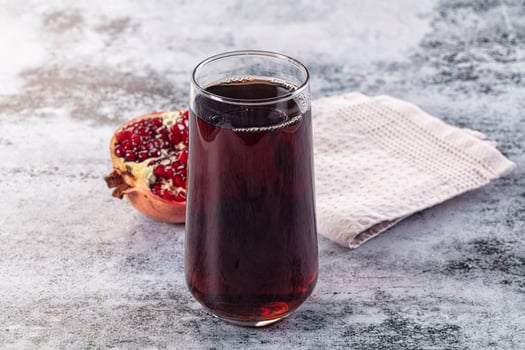 A glass of pomegranate juice next to a pomegranate photo