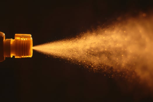 Spraying yellow liquid on dark background creating golden mist photo