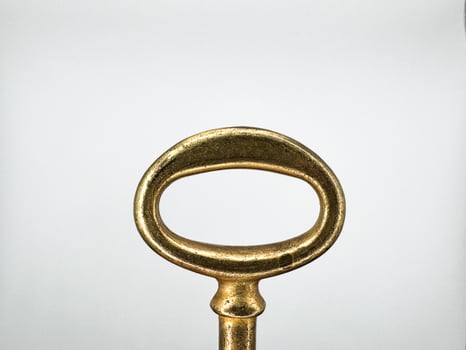 Golden metal key from an old chest on a white background in the center of the image top view photo