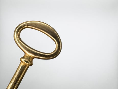 Golden metal key from an old chest on the left on a white background macro top view photo