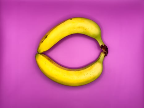 Two bright yellow bananas create a circle, top view, centered in the image photo