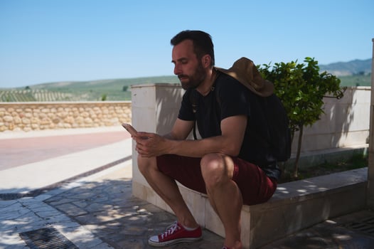 Traveler Sitting Outdoors Using a Smartphone Among Scenic Landscapes photo