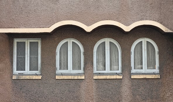 Four white wooden windows on brown or red rough wall. photo