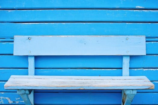 Simple blue wooden bench against a vibrant blue wall photo