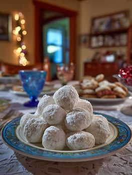 A plate of snowballs cookies on a decorated plate at a holiday gathering. photo