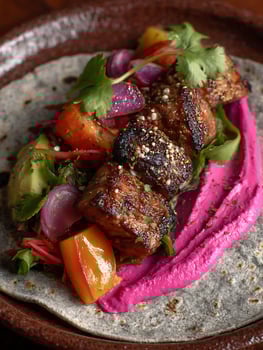 Grilled Meat Skewers on a Flatbread with Beetroot Hummus and Fresh Vegetables. photo