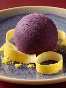 Gourmet Purple Sphere Dessert with Lemon Zest on a Textured Plate. photo