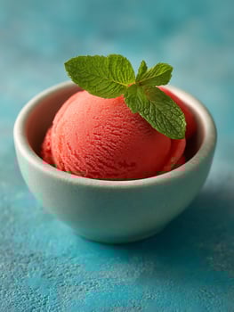 Refreshing Scoop of Red Sorbet in a Teal Bowl with Mint Garnish. photo