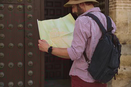 Male Tourist Explores Historic City with Map and Backpack in the Outdoors photo