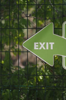 Green exit sign pointing left in nature setting photo