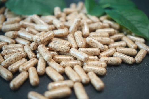 Natural supplement capsules scattered on a dark surface photo