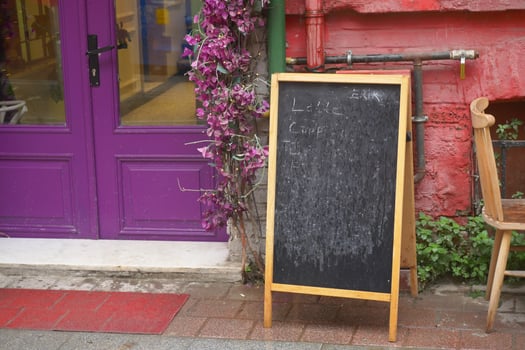 Chalkboard menu stands outside a colorful cafe photo