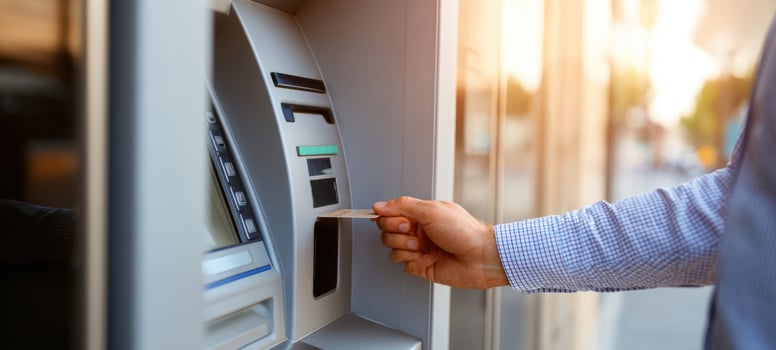 The person withdrawing cash from an ATM during a sunny day. photo