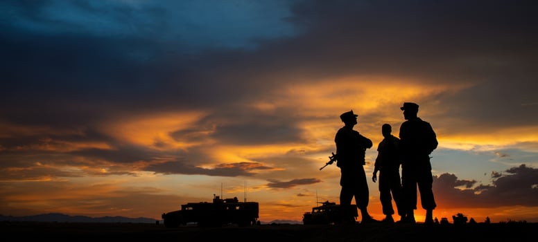 The soldiers silhouetted against a vibrant sunset sky during a military operation. photo