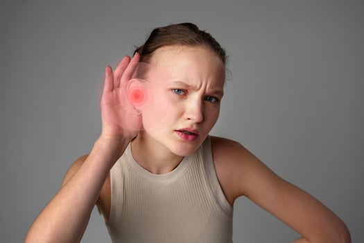 Young woman experiencing ear pain and discomfort while holding her hand to her ear in a neutral setting photo