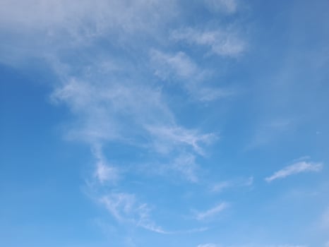 Clear blue sky with soft, scattered white clouds creating a calm and peaceful atmosphere, perfect for nature or weather-themed visuals photo