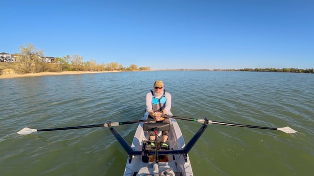 senior rower in coastal rowing shell on lake at Colorado foothills, spring scenery photo