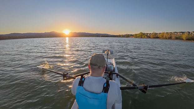 senior rower in coastal rowing shell on lake at Colorado foothills, spring sunset scenery photo